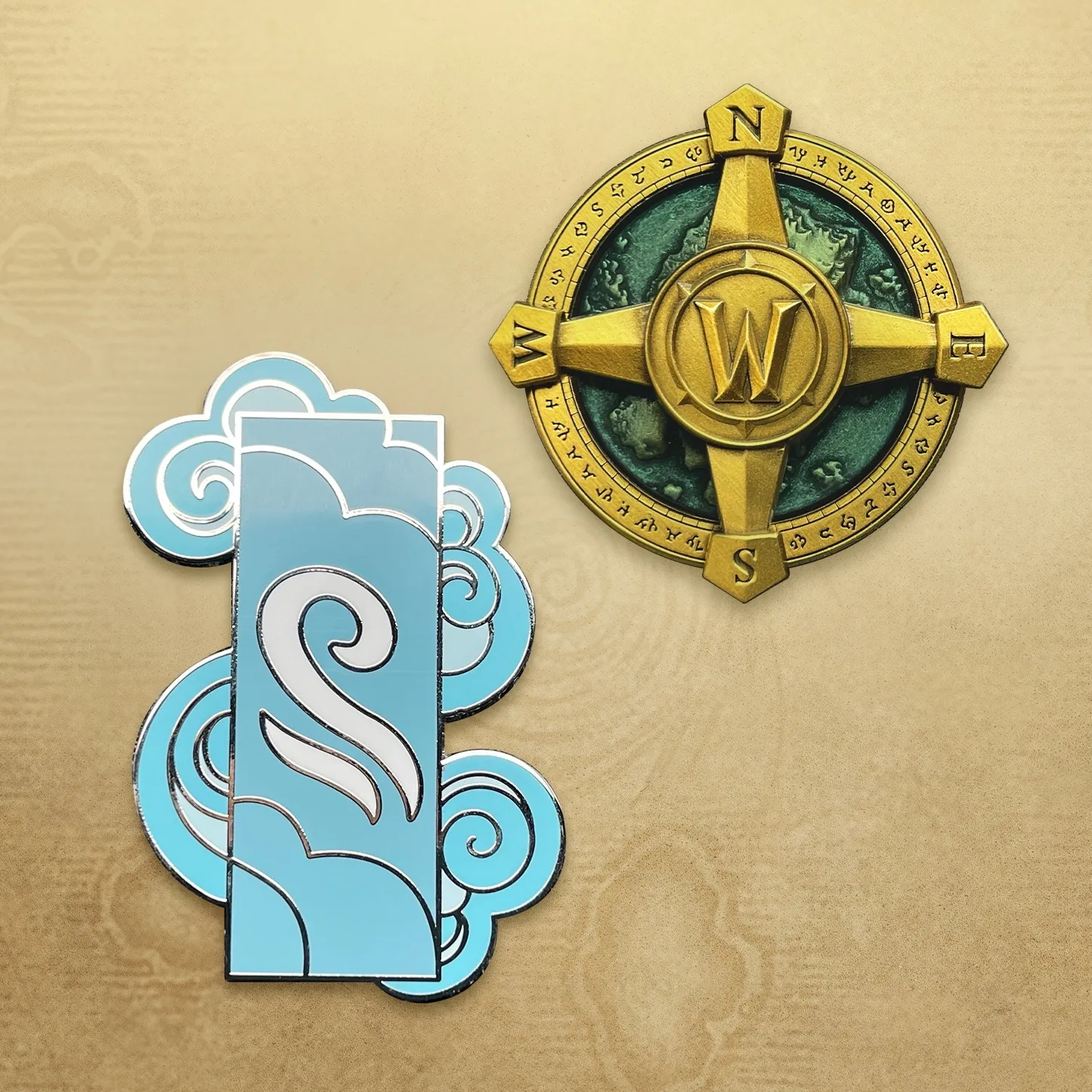 The two collectible pins of the Collector’s Edition, a blue cloud and a golden compass with the W of Warcraft