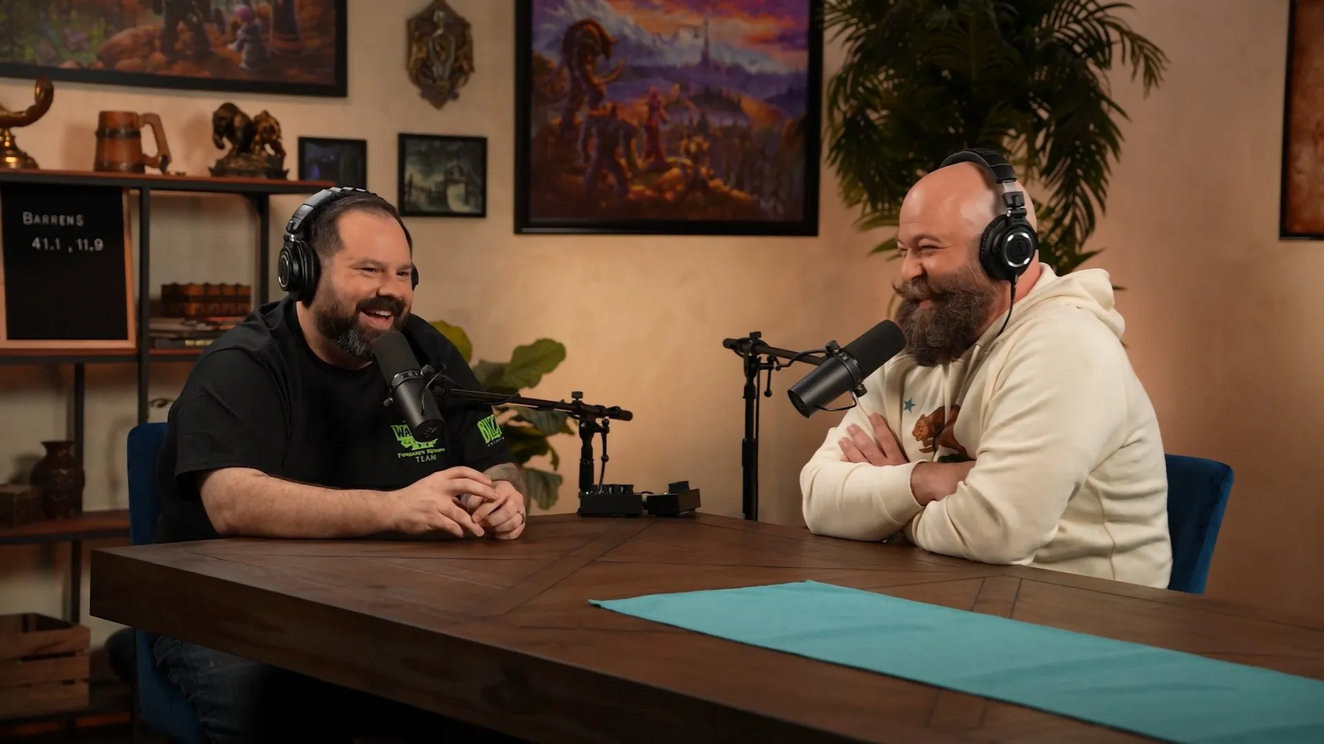 Two men with headphones laughing at a wooden table in a podcast studio, the official image of episode 4 of The WoW: Forever Podcast