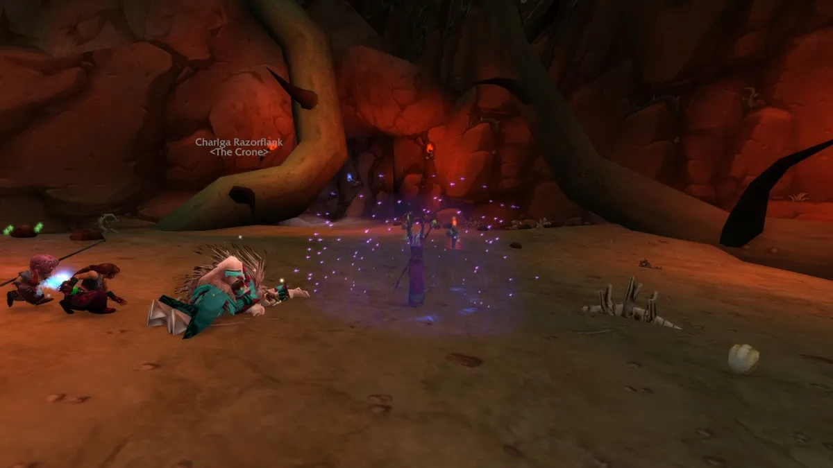 A Mage casts in a purple glow next to a fallen quilboar, with Charlga Razorflank in the background