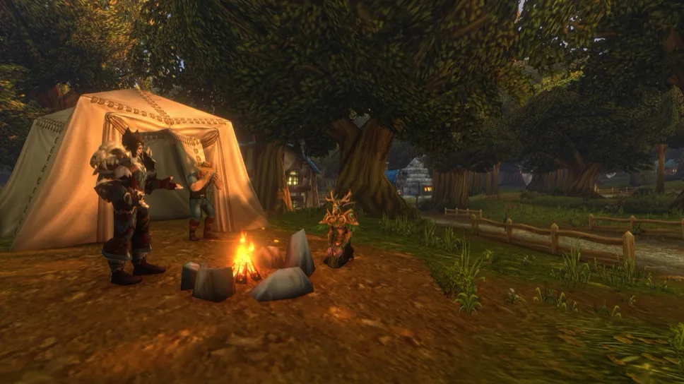 Due giocatori accanto a un falò davanti a una grande tenda, con un piccolo spirito degli alberi vicino al fuoco, ai margini di un villaggio sotto alberi alti, un'immagine di Blizzard di World of Warcraft: Forever