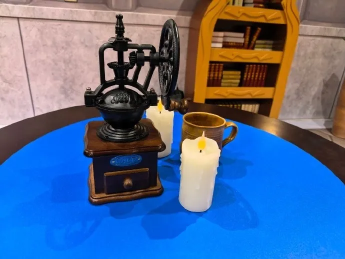 An old coffee grinder, a mug and two candles on a blue table in front of a bookcase, a photo of the Forever Party in Shanghai