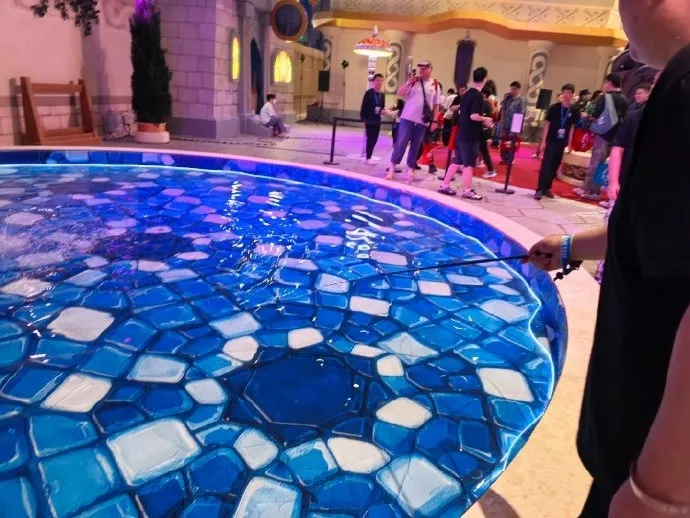 A round fountain with blue and white tiles, with visitors walking past violet buildings, a photo of the Forever Party in Shanghai