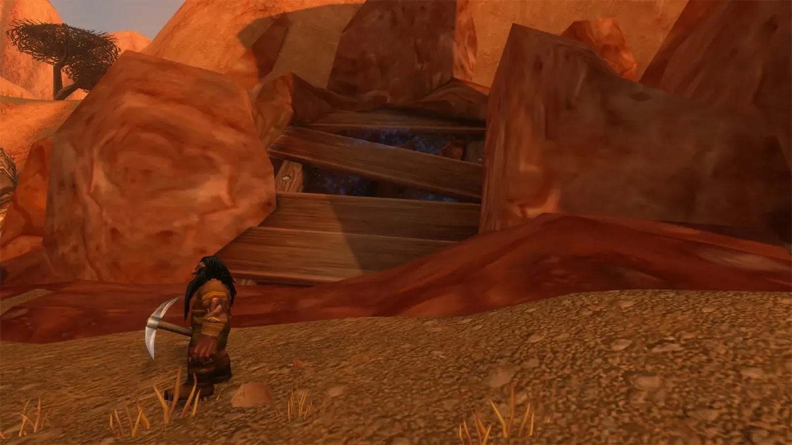 Una abertura tapiada entre rocas rojas en Bael Modan con un minero enano delante, una captura de pantalla de la beta de World of Warcraft: Forever