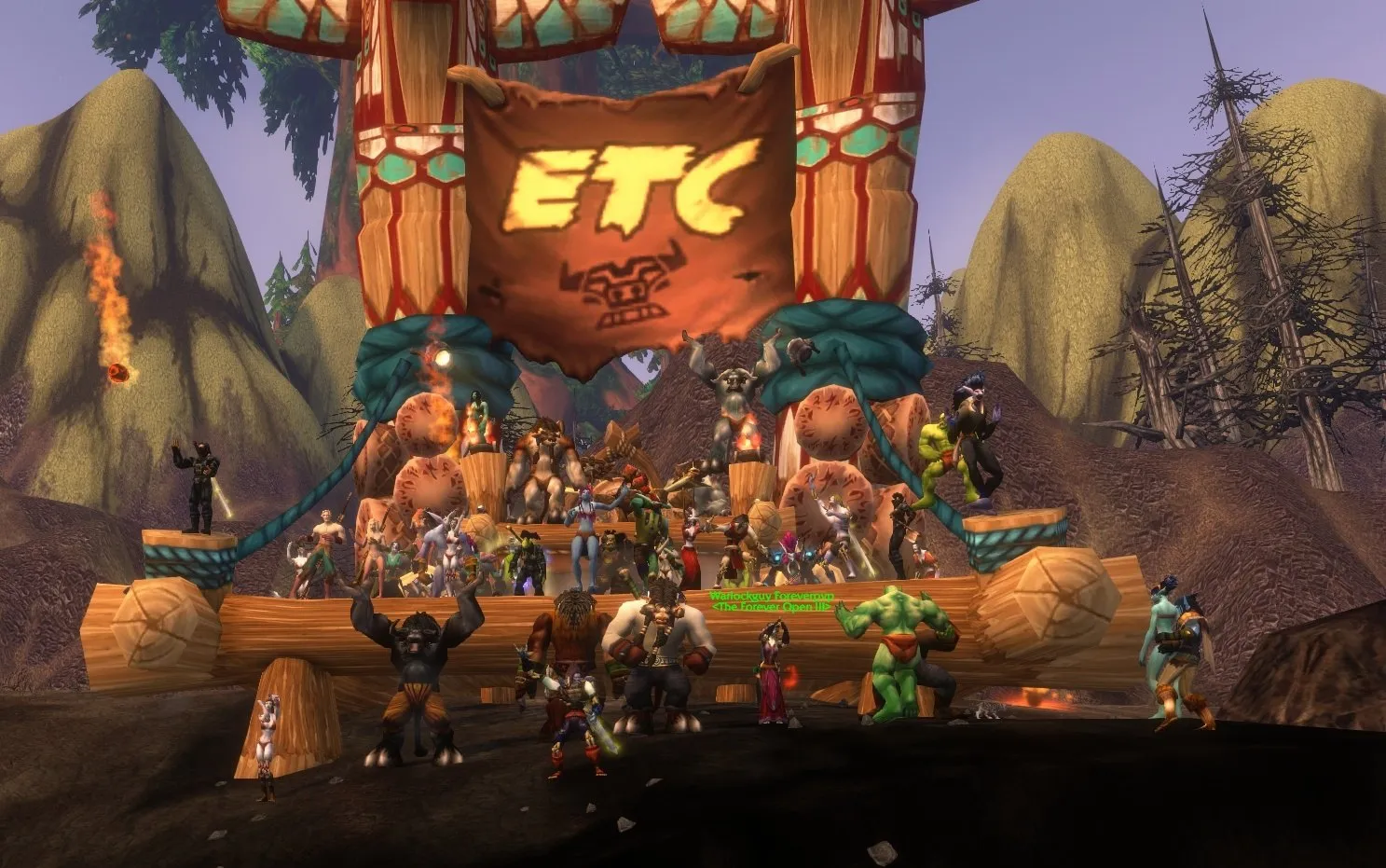 Players of the Forever Open crowd in front of a wooden stage with an ETC banner, where the Tauren Chieftains perform, a screenshot from the beta of World of Warcraft: Forever