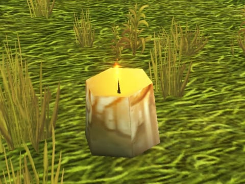 The Incense Candle, a thick burning candle in the grass